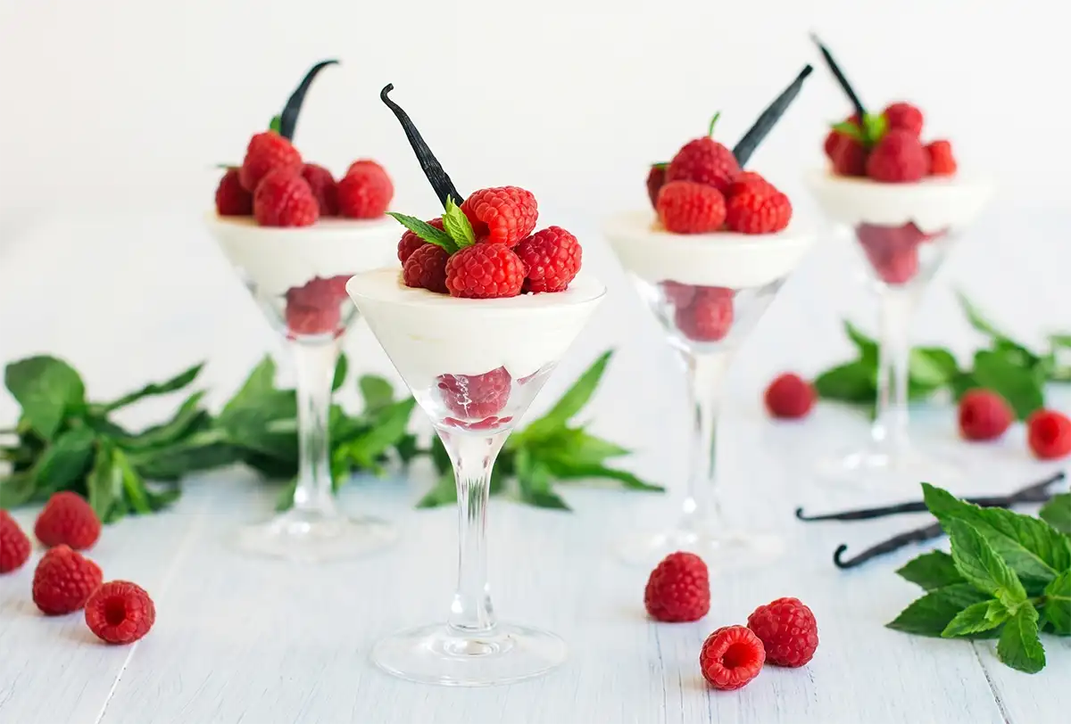 Raspberry and vanilla verrines surrounded by fresh raspberries and mint
