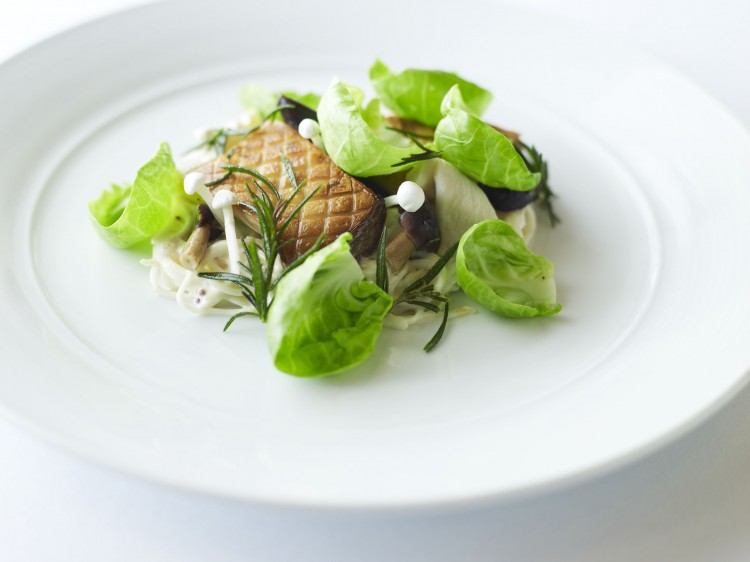 Plated main course with green leaves on a white plate